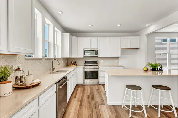 a kitchen with a sink white cabinets and white appliances