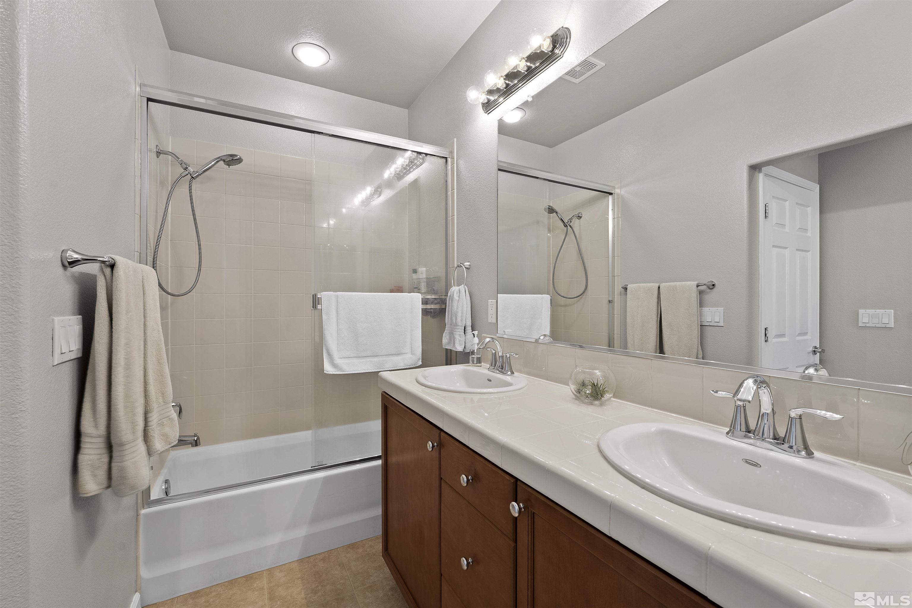 2212 Grosvenor Reno, NV 89509 - Photo 27 of 36 a bathroom with a double vanity sink a mirror a shower and a bathtub