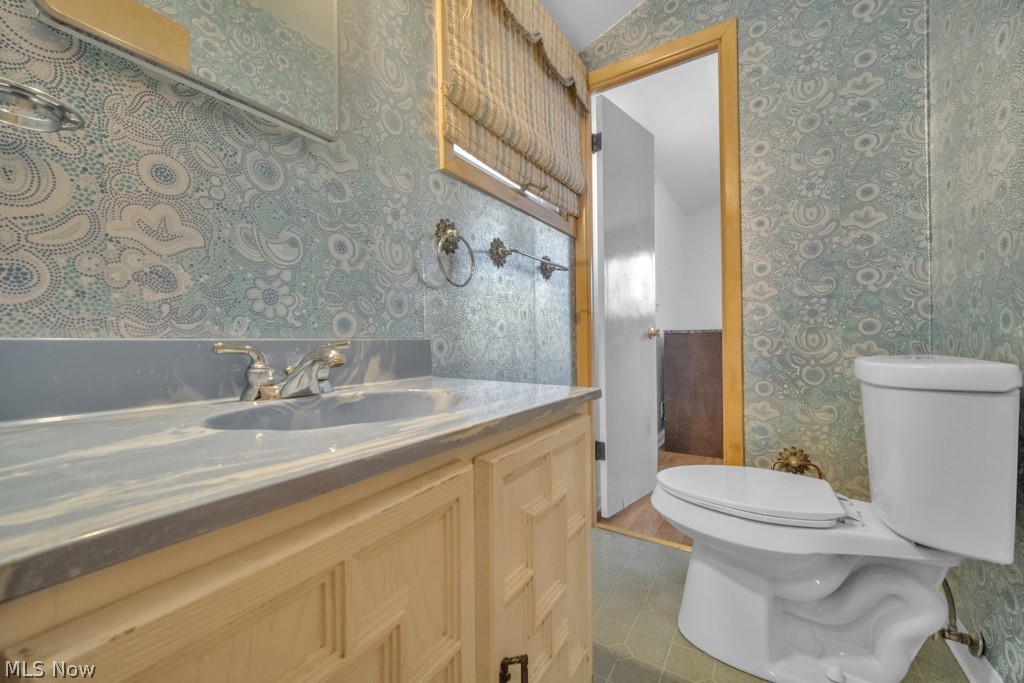 6846 Revere Road Cleveland, OH 44130 - Photo 24 of 30 Bathroom featuring wallpapered walls, vanity, and dark tile patterned flooring