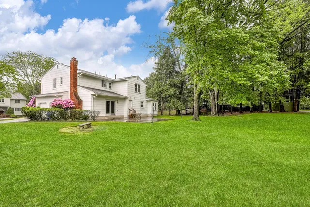 a view of a white house with a big yard and large trees