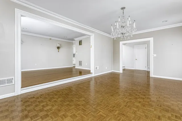 wooden floor in an empty room with a chandelier