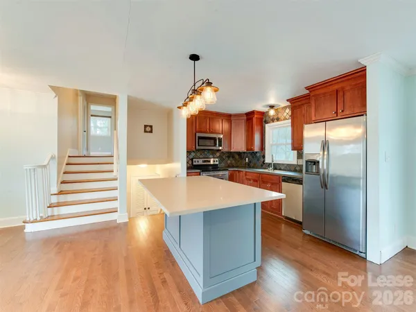 a large kitchen with stainless steel appliances granite countertop a lot of cabinets and wooden floor