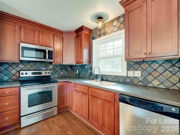a kitchen with stainless steel appliances granite countertop a sink a stove a microwave and wooden cabinets