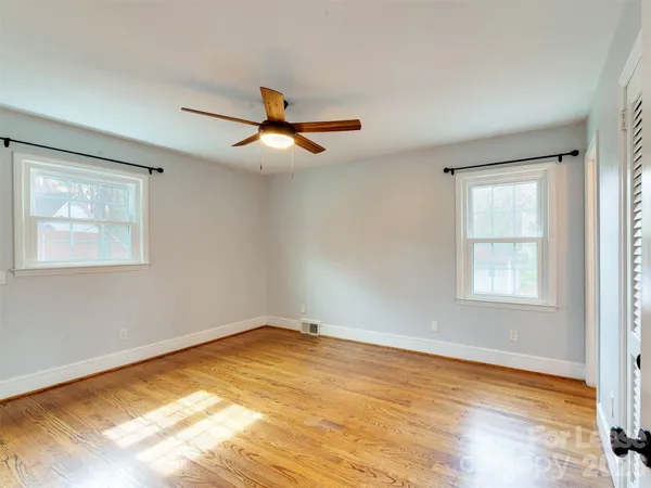 a view of empty room with wooden floor and fan
