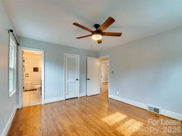 a view of empty room with wooden floor and fan