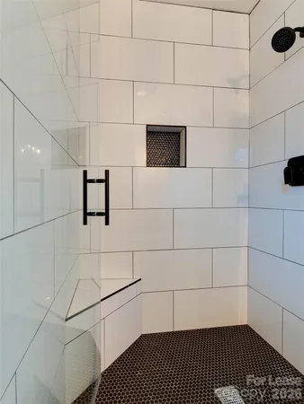 a bathroom with a shower and a tiled wall