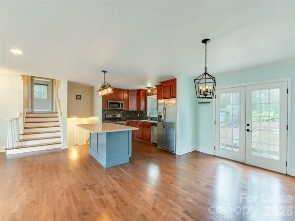 a kitchen with stainless steel appliances kitchen island granite countertop a refrigerator a stove and a wooden floors