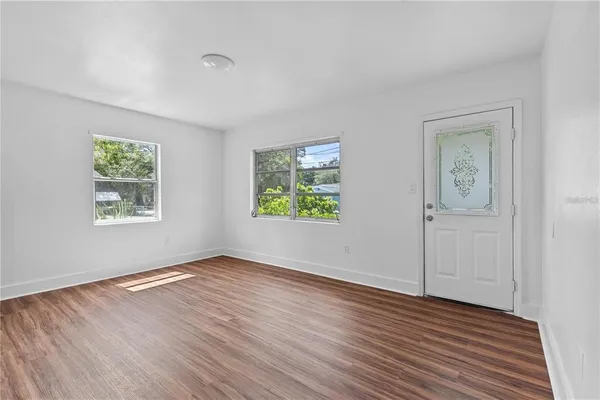 a view of an empty room with window and wooden floor