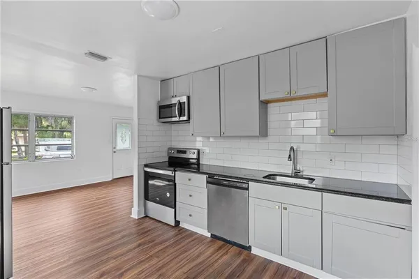 a kitchen with stainless steel appliances granite countertop a sink a stove a microwave and wooden floors