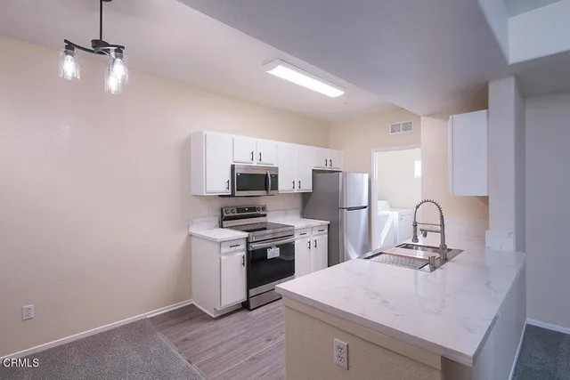 a kitchen with a sink stainless steel appliances and white cabinets