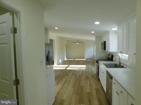 a view of a kitchen with a sink and dishwasher a refrigerator with wooden floor