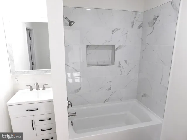 a bathroom with a bathtub sink vanity and mirror