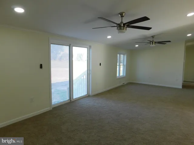 an empty room with ceiling fan and window