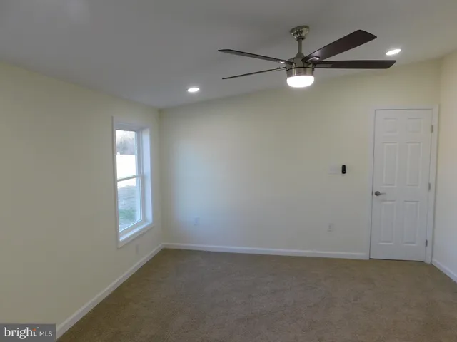 an empty room with a window and a fan