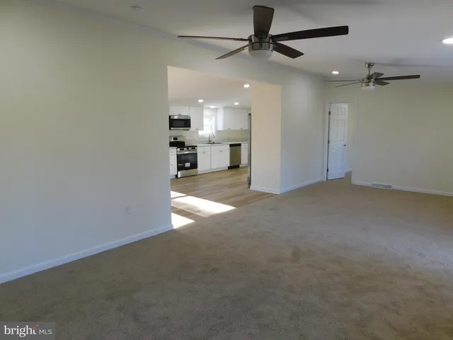 an empty room with a ceiling fan and windows