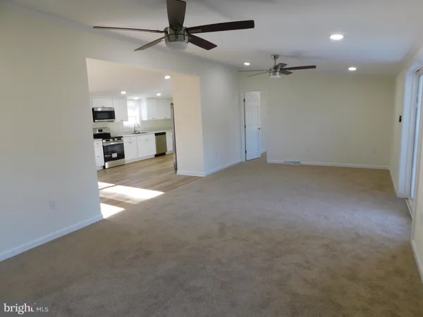 an empty room with chandelier fan and windows