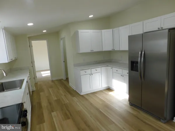 a kitchen with a sink a refrigerator and wooden floor