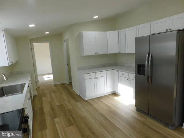 a kitchen with a sink a refrigerator and wooden floor