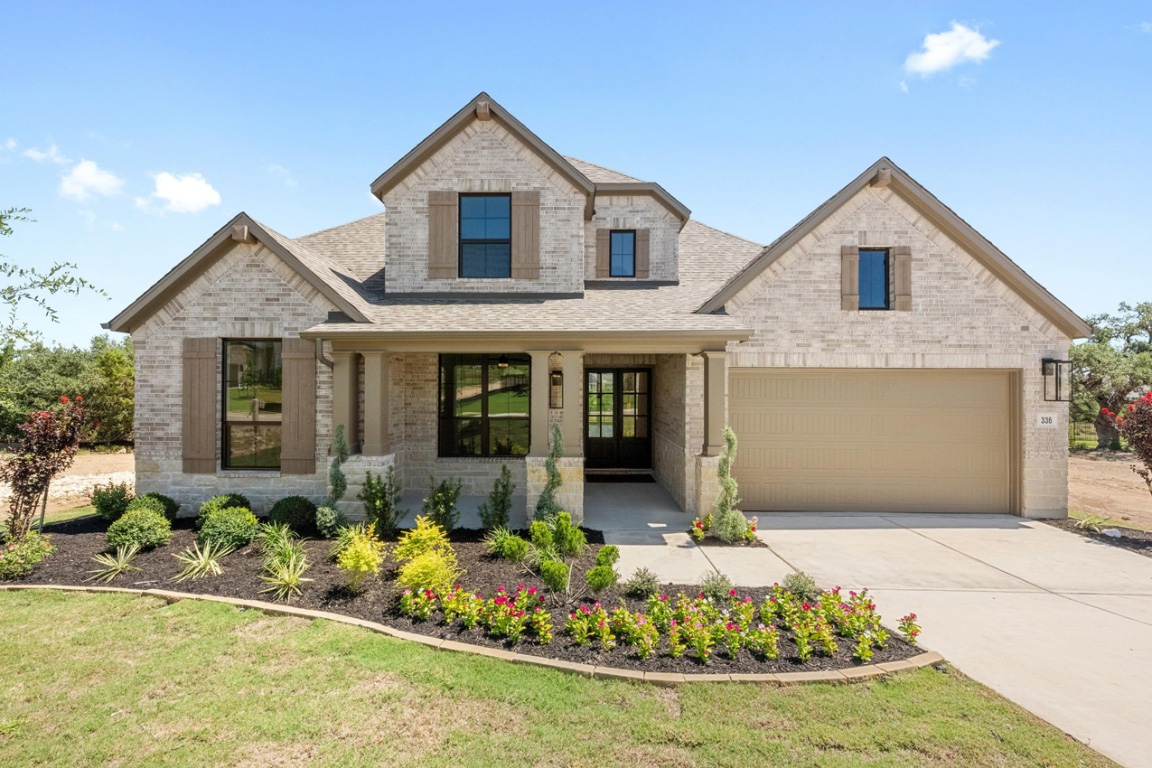 French country inspired facade featuring brick siding, covered porch, concrete driveway, a garage, and roof with shingles