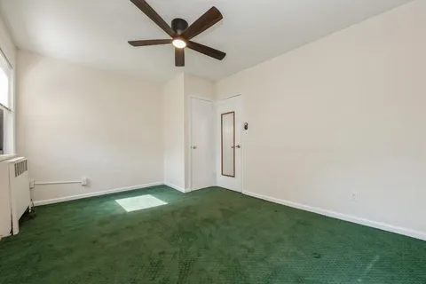 an empty room with a ceiling fan and window
