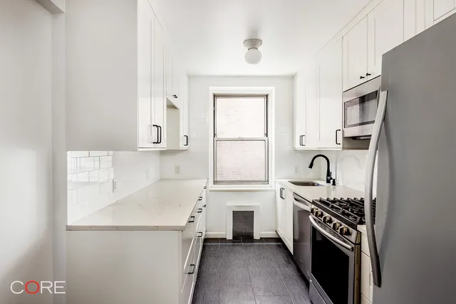 a kitchen with stainless steel appliances a refrigerator a sink and white cabinets