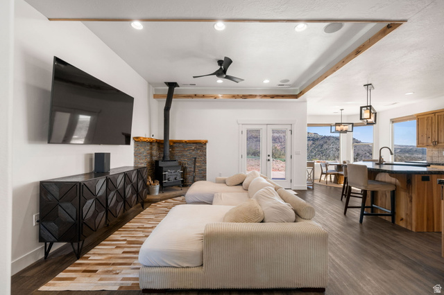 62 North Lucky 7 Road Veyo, UT 84782 - Photo 5 of 43 Living area featuring dark wood-type flooring, a ceiling fan, a wood stove, a raised ceiling, and french doors