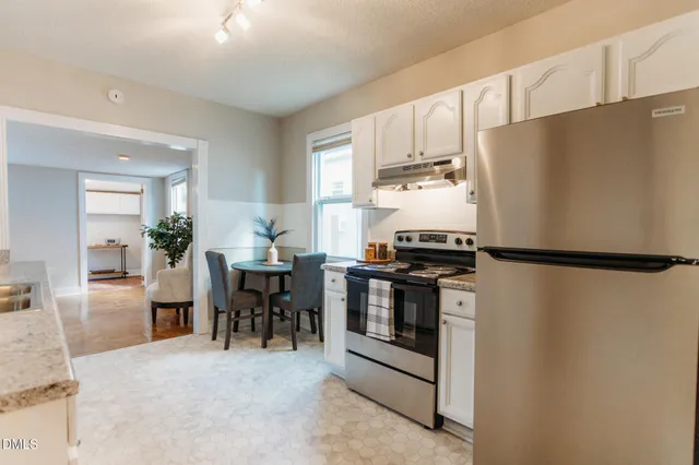 a kitchen with stainless steel appliances a refrigerator a stove a dining table and chairs