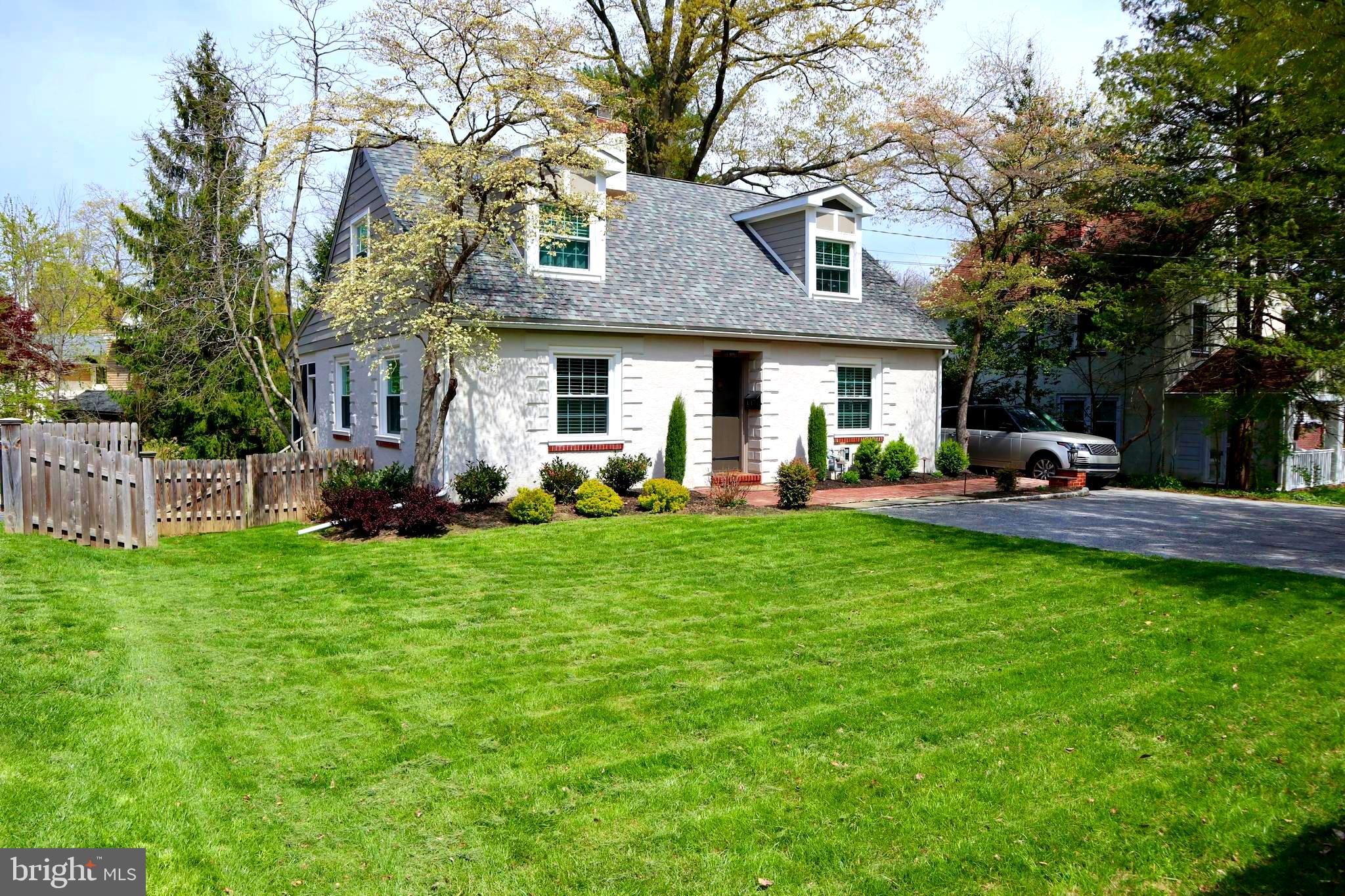 a front view of a house with a garden and trees