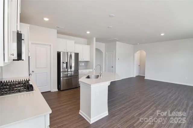 a view of a kitchen with a sink refrigerator and wooden floor