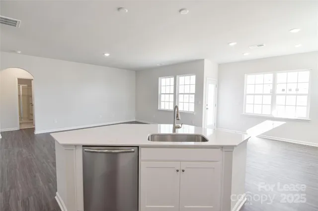 a room with a sink dishwasher and white cabinets with wooden floor