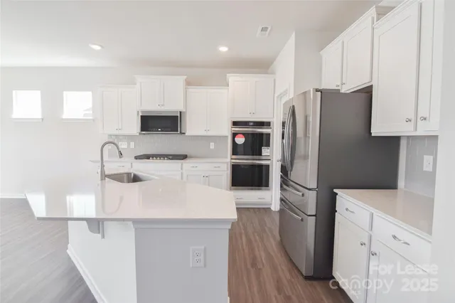 a kitchen with kitchen island a white counter top space cabinets and stainless steel appliances