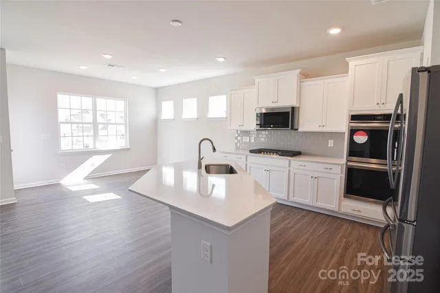 a kitchen with a sink a microwave a refrigerator and cabinets