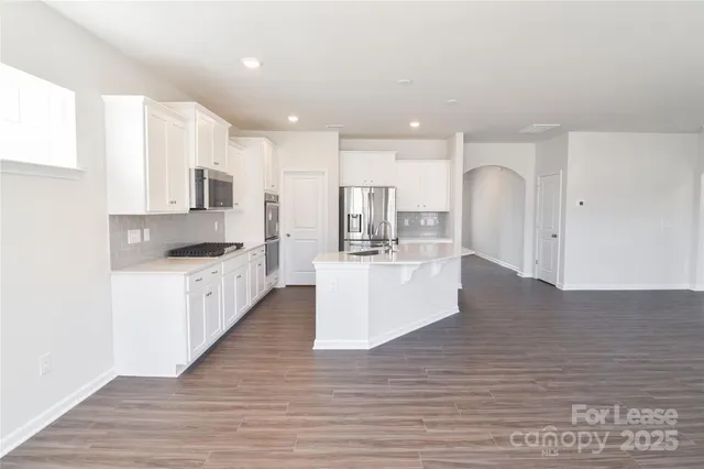a large white kitchen with kitchen island a sink a center island stainless steel appliances and a cabinets