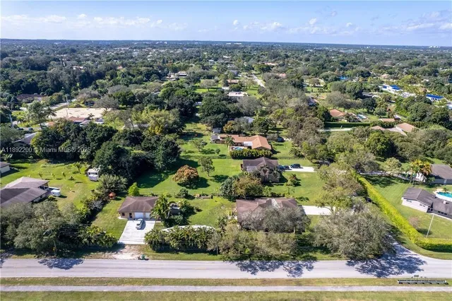 an aerial view of a residential houses with outdoor space and trees