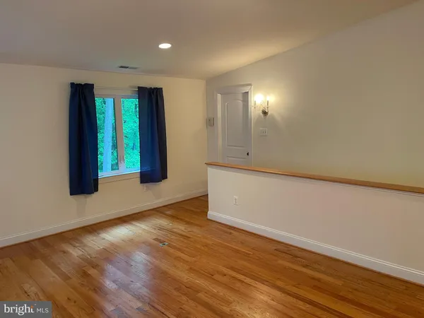 a view of an empty room with window wooden floor and front door