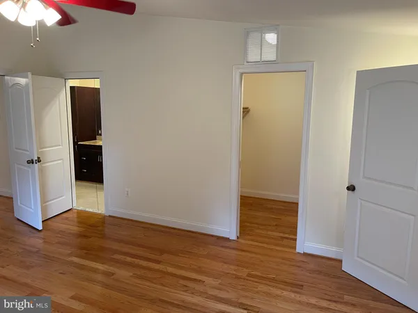 a view of a hallway with wooden floor and a bathroom