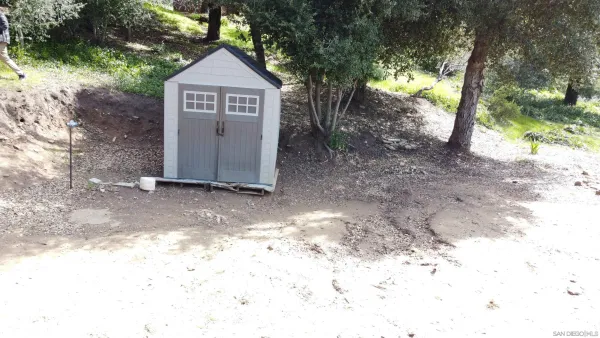a view of a small yard in front of a house with large trees