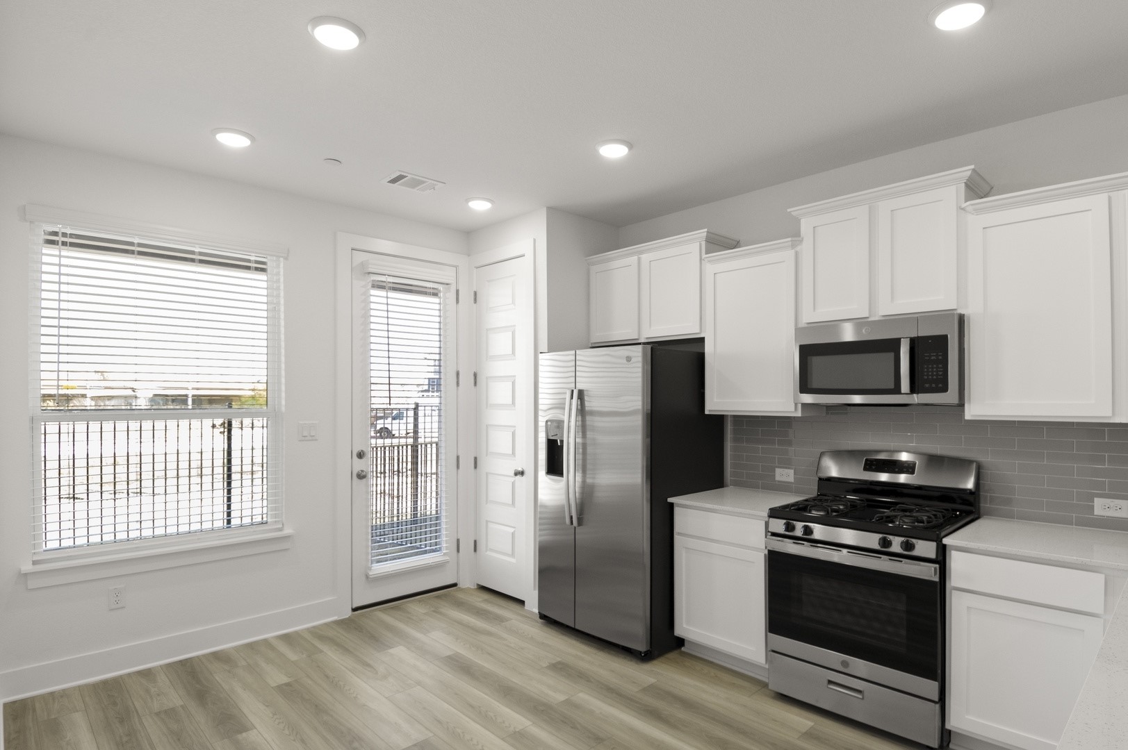 18909 Schultz Lane, Unit 1002 Round Rock, TX 78664 - Photo 13 of 24 Kitchen featuring stainless steel appliances, white cabinets, light wood-style floors, backsplash, and recessed lighting