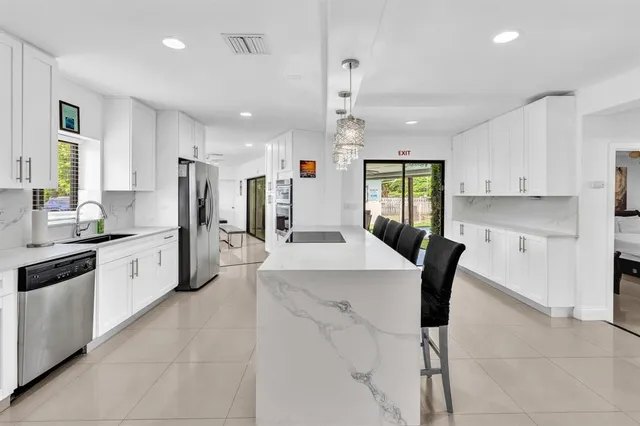 a large kitchen with stainless steel appliances kitchen island granite countertop a table chairs sink refrigerator and cabinets