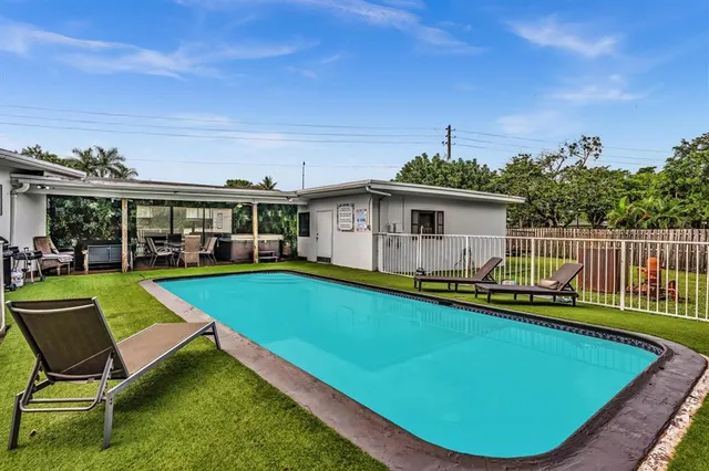 a view of a swimming pool with lawn chairs and a big yard