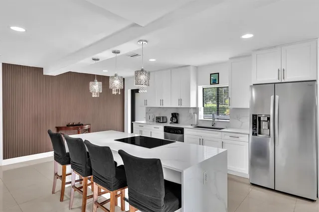 a kitchen with stainless steel appliances a refrigerator a sink a dining table and chairs