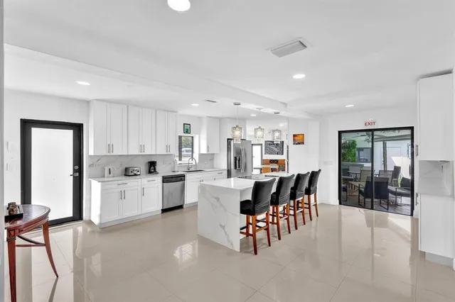 a large white kitchen with a large window and stainless steel appliances