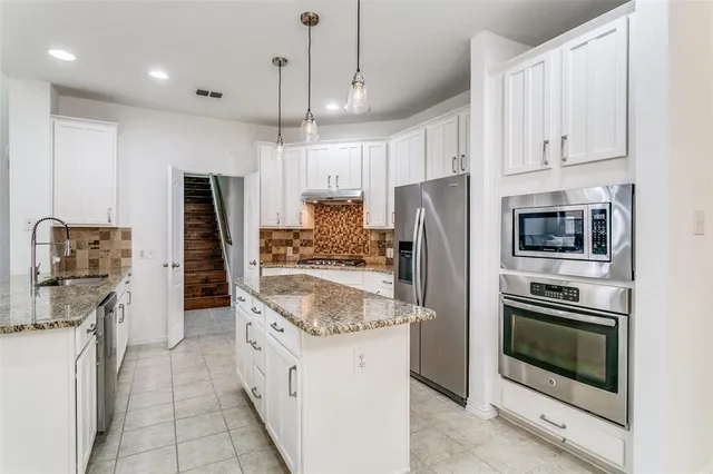 a kitchen with stainless steel appliances granite countertop a refrigerator a stove and a sink