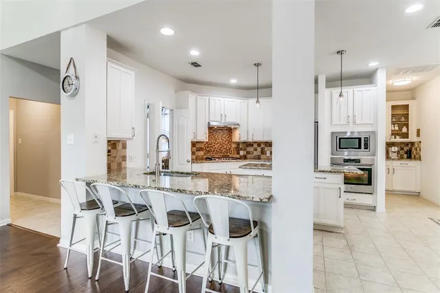 a kitchen with stainless steel appliances kitchen island granite countertop a refrigerator and a stove top oven