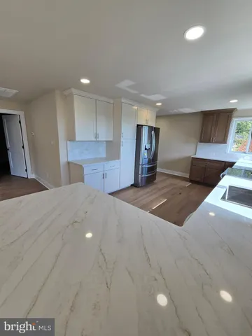 a view of kitchen with stainless steel appliances refrigerator oven and wooden floor