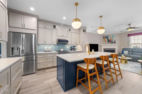 a kitchen with stainless steel appliances kitchen island granite countertop a stove a sink dishwasher a island with wooden cabinets and refrigerator