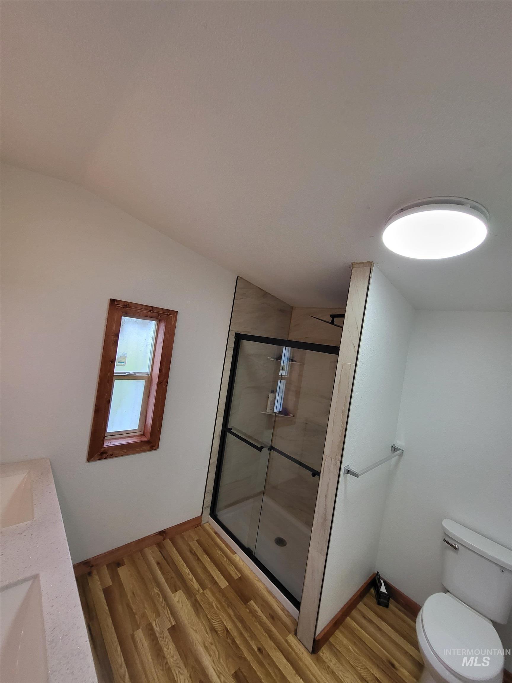 89 Waterfall Loop Orofino, ID 83544 - Photo 4 of 6 Full bathroom featuring a shower stall, light wood-style flooring, double vanity, and lofted ceiling