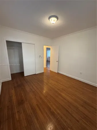 a view of an empty room with wooden floor and closet