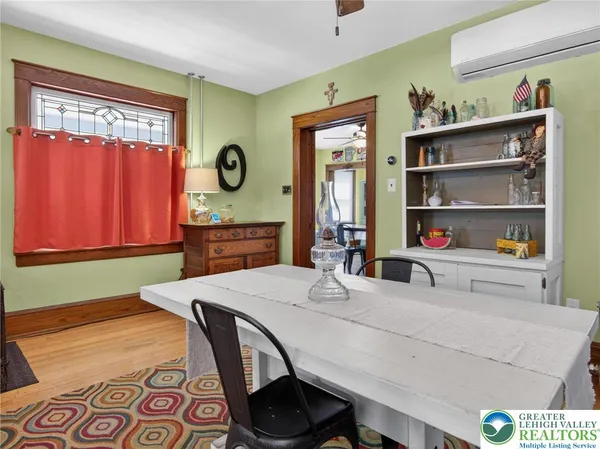 a dining room with wooden floor a chandelier fan a wooden table and chairs