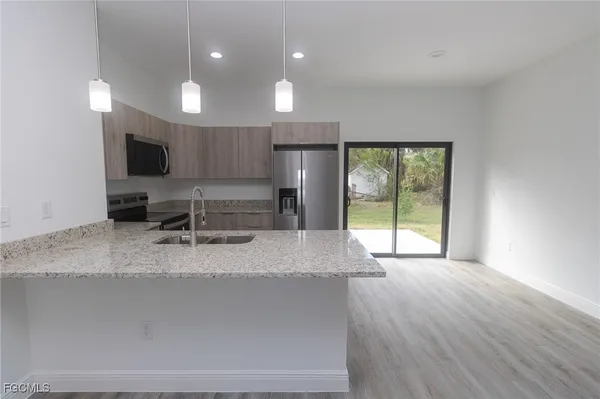 a large kitchen with stainless steel appliances a large counter top a stove a sink and a large window